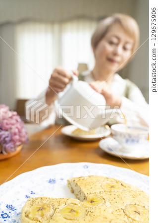 A senior woman baking a cake and making tea to enjoy her own time 129675906