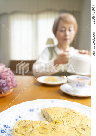 A senior woman baking a cake and making tea to enjoy her own time A senior woman baking a cake and making tea to enjoy her own time 129675907