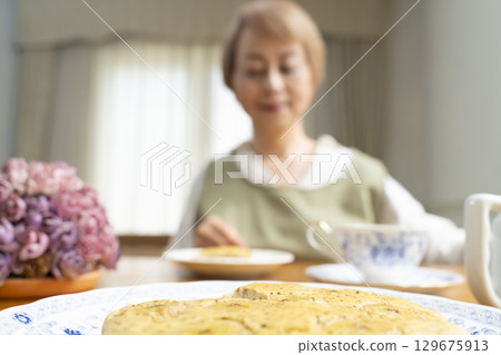 A senior woman baking a cake and making tea to enjoy her own time 129675913