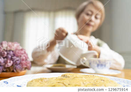 A senior woman baking a cake and making tea to enjoy her own time A senior woman baking a cake and making tea to enjoy her own time 129675914
