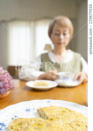 A senior woman baking a cake and making tea to enjoy her own time 129675916
