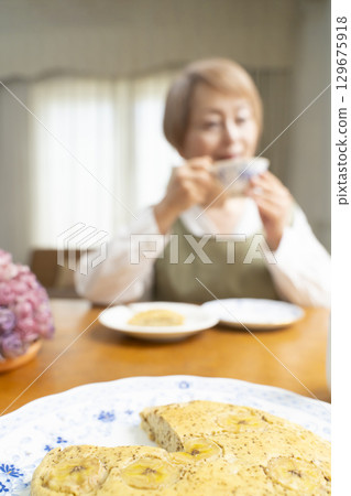 A senior woman baking a cake and making tea to enjoy her own time 129675918