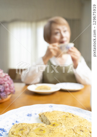 A senior woman baking a cake and making tea to enjoy her own time 129675919