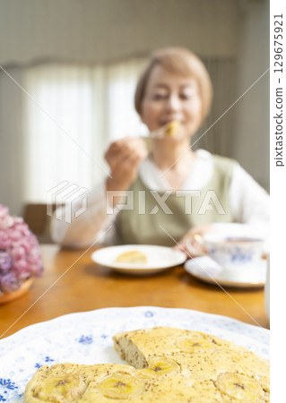 A senior woman baking a cake and making tea to enjoy her own time A senior woman baking a cake and making tea to enjoy her own time 129675921