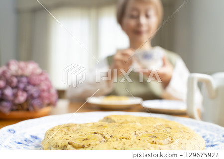 A senior woman baking a cake and making tea to enjoy her own time A senior woman baking a cake and making tea to enjoy her own time 129675922