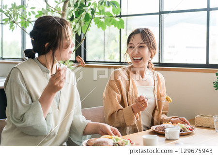 A woman eating a delicious lunch with her female friends (girls' gathering) A woman eating a delicious lunch with her female friends (girls' gathering) 129675943