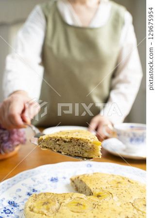 Senior woman baking a cake and making tea, enjoying her own time. No face. 129675954
