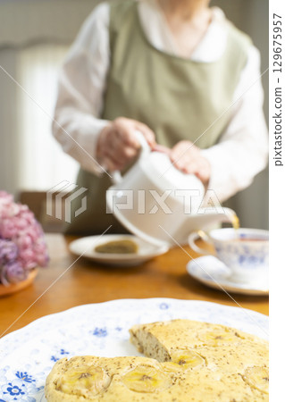 Senior woman baking a cake and making tea, enjoying her own time. No face. 129675957