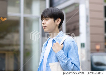 Portrait of a young man walking in the city 129676842