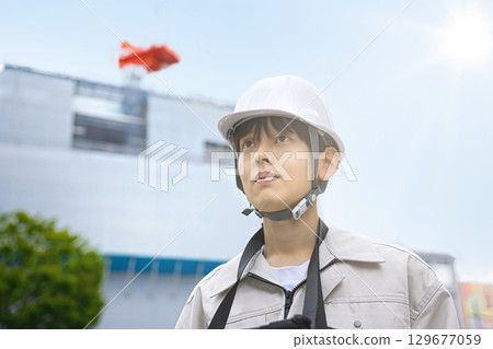 穿著工作服的年輕商人在建築工地上看著平板電腦 129677059