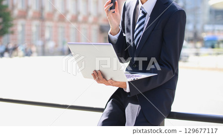 一位年輕的商人在商業區用智慧型手機交談 129677117