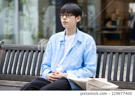 坐在城市長椅上的年輕人 129677409