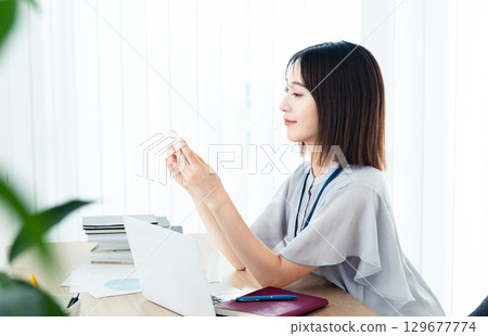 Business woman looking at a smartphone in the office Business woman looking at a smartphone in the office 129677774