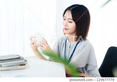 Business woman looking at a smartphone in the office Business woman looking at a smartphone in the office 129677779