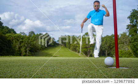 Golfer putting ball on the green golf, lens flare on sun set evening time. Golfer hitting golf ball. Golfer putting ball on the green golf, lens flare on sun set evening time. Golfer hitting golf ball. 129677892