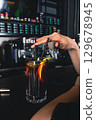Female hands with cocktail at bar counter, close-up. Unrecognizable woman chilling at lounge bar. 129678945