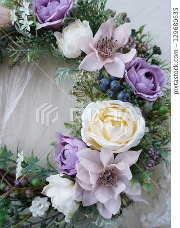 A wreath of white and purple flowers placed on lace fabric A wreath of white and purple flowers placed on lace fabric 129680635