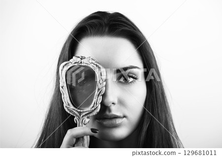 Beautiful woman covers her one eye with old mirror 129681011