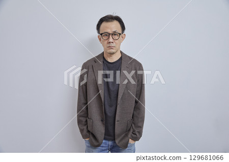 Handsome Asian businessman in suit with eyeglass smile and look at camera on grey background. 129681066