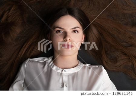 Woman with long brown hair lying on ground Woman with long brown hair lying on ground 129681145