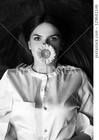 Woman with long hair hair and flower in her mouth Woman with long hair hair and flower in her mouth 129681146