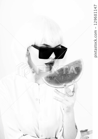 Studio portrait of woman with white wig holding slice of red watermelon 129681147