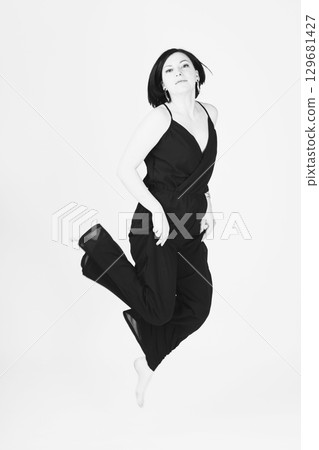 Happy woman with black clothes jumping to air Happy woman with black clothes jumping to air 129681427