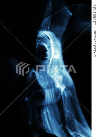 Light trails of light painting blue vivid color woman portrait 129681429