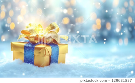 Golden Gift Box with Blue Ribbon and Sparkling Bow on Snowy Wint 129681857