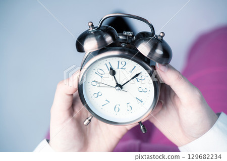 Top view of woman holding retro clock in her hands 129682234