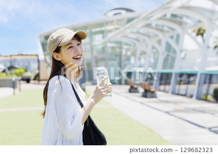 一位戴著帽子在戶外補水的女士 129682323