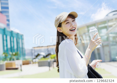 一位戴著帽子在戶外補水的女士 129682324