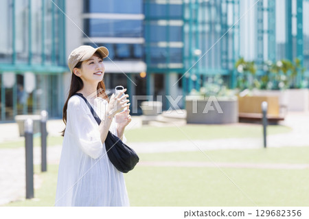 一位戴著帽子在戶外補水的女士 129682356