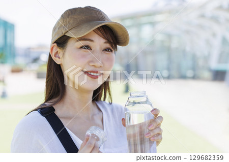一位戴著帽子在戶外補水的女士 129682359