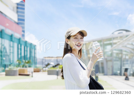 一位戴著帽子在戶外補水的女士 129682360