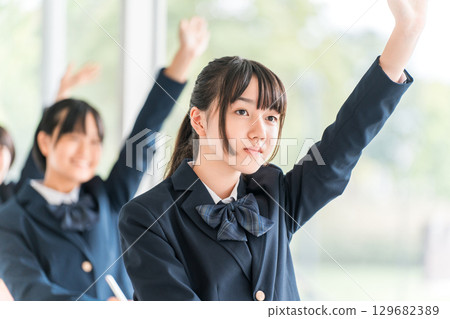 Active elementary school students, junior high school students, high school students, and high school girls (friends) in uniforms raising their hands during class in a school classroom 129682389