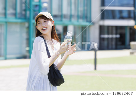 A woman wearing a cap hydrating outdoors 129682407