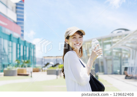 A woman wearing a cap hydrating outdoors 129682408