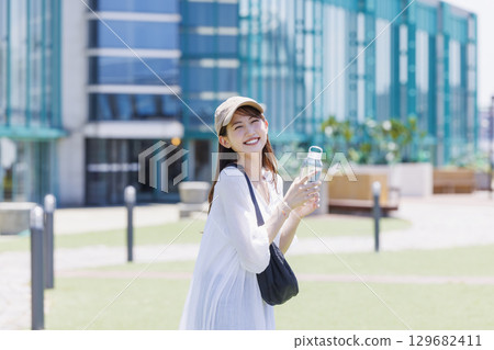 A woman wearing a cap hydrating outdoors A woman wearing a cap hydrating outdoors 129682411