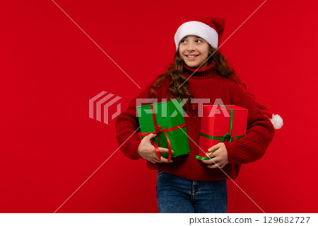 Girl in Santa hat holds Christmas presents 129682727
