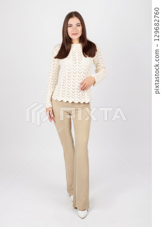 Beautiful woman portrait with white sweater and beige trousers Beautiful woman portrait with white sweater and beige trousers 129682760