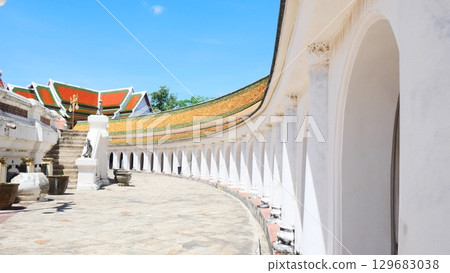 Beautiful arched walkway and traditional temple roof at a Buddhist temple in Thailand 129683038