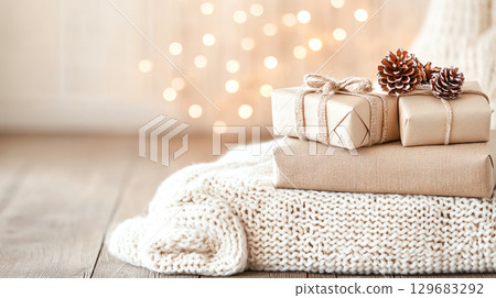 Wrapped holiday festive seasonal Christmas New Year presents gifts with decorative accents create cozy atmosphere, perfect for festive celebrations. soft knit background adds warmth to scene 129683292