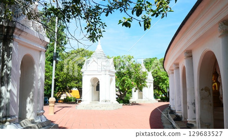 White bell-shaped pagodas and a curved walkway with arches in a Thai temple White bell-shaped pagodas and a curved walkway with arches in a Thai temple 129683527