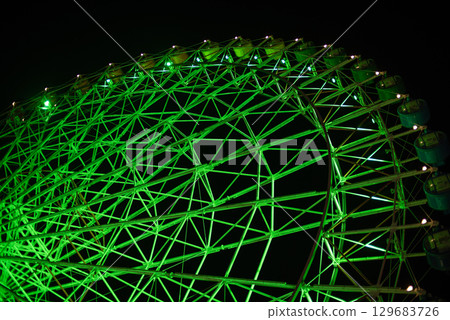 Illuminated green Ferris wheel against dark night sky 129683726
