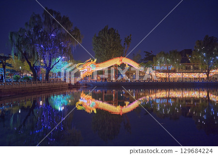 Illuminated dragon lantern reflecting on a calm Shichahai lake at night in central Beijing, China 129684224