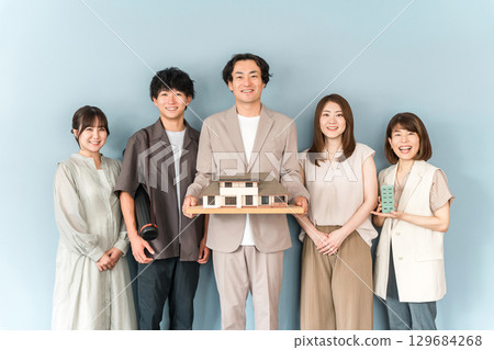 房屋製造商、設計辦公室或建築公司的男女員工拿著建築模型或房屋模型 129684268