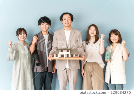 Male and female staff of a house manufacturer, design office, or construction company holding an architectural model or house model 129684270