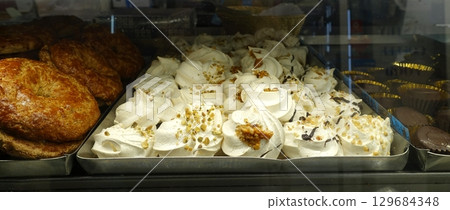 Freshly baked meringues with hazelnut crumbs on top. 129684348