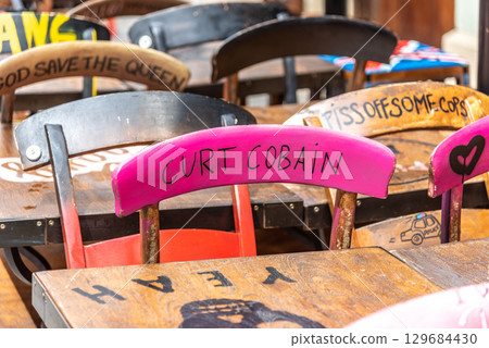 Colorful chairs with graffiti and names of famous rock musicians in a cafe setting in Bratislava, Slovakia Colorful chairs with graffiti and names of famous rock musicians in a cafe setting in Bratislava, Slovakia 129684430